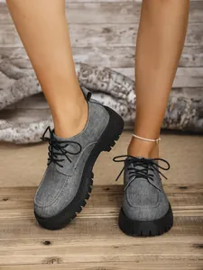 Detailansicht der grauen Schnürschuhe mit Plateausohle und Denim-Textur am Fuß