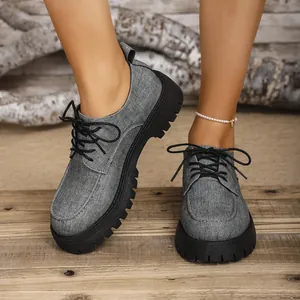 Graue Plateau-Oxford-Schuhe aus Stoff mit schwarzen Schnürsenkeln auf Holz