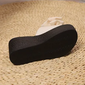 Primer plano de la suela de cuña negra y el lazo beige de la sandalia de verano