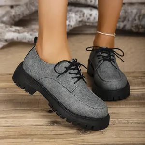 Nahaufnahme graue Vintage-Loafer aus Stoff mit schwarzer dicker Profilsohle auf Holzboden