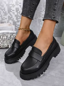 Nahaufnahme schwarzer Loafer mit dicker Plateausohle im britischen Retro-Stil zum Hineinschlüpfen