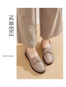 Close-up of stylish breathable taupe leather loafers with bow detail on a woven jute mat.