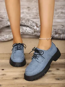 Nahaufnahme von blauen Denim-Loafern mit dicken schwarzen Profilsohlen auf Holz