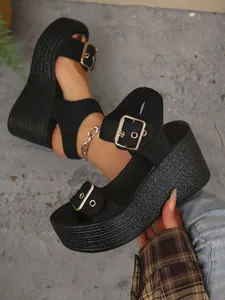 Close-up view of black platform wedge sandals featuring stylish gold buckles and woven texture