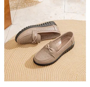 Detail view of breathable beige leather loafers with decorative bow and floral cutouts