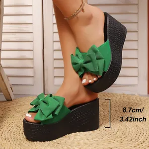 Vista lateral de sandalias de cuña verdes con lazo y altura de tacón de 8,7 cm.