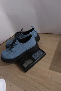 Nahaufnahme von blauen Denim-Plateau-Oxfords, die auf einer Digitalwaage gewogen werden.
