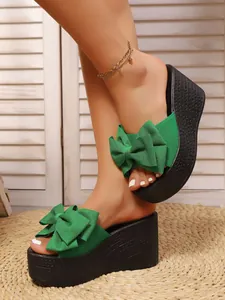 Primer plano de sandalias de cuña verdes con un elegante adorno de lazo grande
