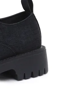 Detailaufnahme der schwarzen Canvas-Textur und der dicken Profilsohle dieses Loafers