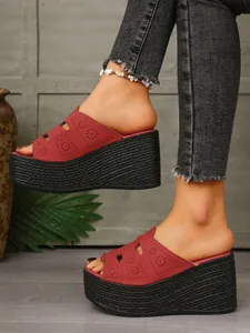 Gros plan de sandales compensées rouges à fleurs découpées au laser au pied