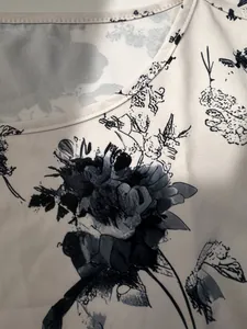 Dettaglio di un top da donna con scollo rotondo e stampa floreale nera su tessuto beige