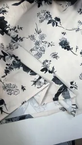 Primo piano di una stampa floreale nera su tessuto estivo beige con dettaglio orlo rifinito