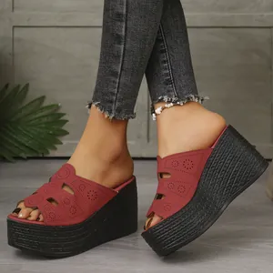Vue détaillée de sandales compensées rouges ajourées portées avec un jean denim