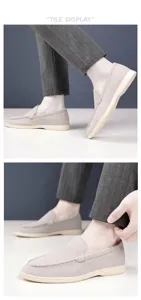 Close-up of light grey suede loafers featuring handmade stitching and a slip-on design.