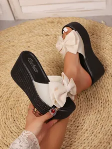 Vista detallada de sandalias de cuña para mujer con lazo crema y suela negra elegante