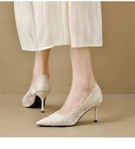Vista lateral detallada de elegantes tacones de encaje blanco con punta fina usados por una modelo
