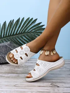 Détail de sandales à plateforme blanches pour femmes avec motifs floraux ajourés.