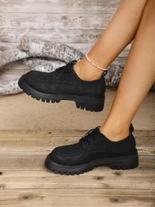 Detailansicht von klassischen schwarzen Damen-Loafers mit dicker Sohle im britischen Stil