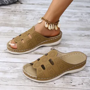 Gros plan de mules compensées marron avec motif floral découpé au laser pour femmes
