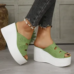 Gros plan de mules à talons compensés verts avec plateforme tressée blanche et motifs ajourés.