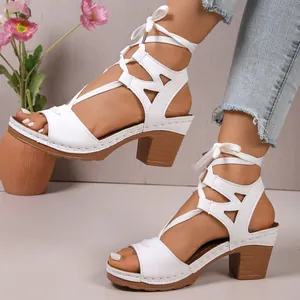 Primo piano di sandali stringati bianchi con tacco a blocco e design peep-toe su modella