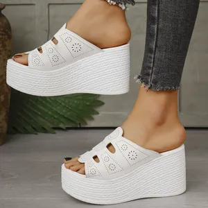Détail des sandales compensées blanches avec motifs floraux perforés au pied