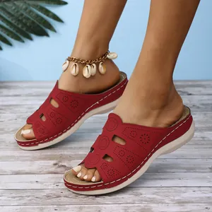 Détail de sandales compensées rouges pour femmes avec motifs floraux découpés au laser