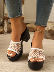 Detail view of stylish white honeycomb mesh platform slides with black chunky heels.