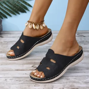 Vue détaillée de mules compensées noires portées avec une chevillère en coquillage.