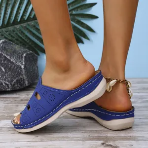 Détail de sandales compensées bleues avec motifs floraux découpés au laser et semelle épaisse