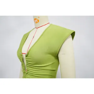 Macro detail view of a light green slim-fit dress with deep V-neck and ruched center
