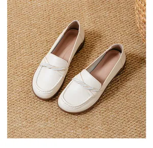 High-angle view of comfortable cream slip-on loafers on a textured woven mat background