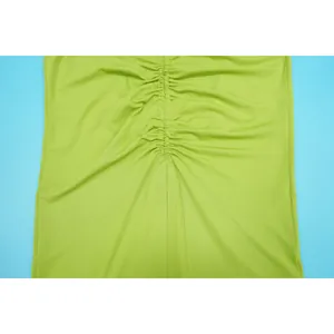 Detailed macro view showing the elegant ruched fabric texture of a lime green dress