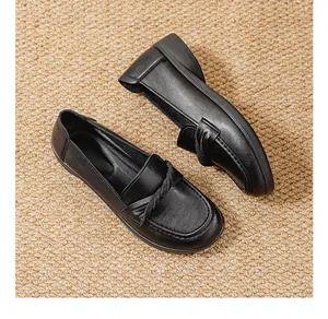 Detailed top view of black leather loafers with twist detail on a woven straw mat