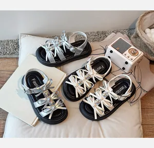 Detail shot of girls' bow sandals in silver and white colors with thick soles