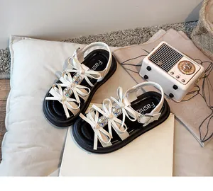 Detailed view of white girls' sandals featuring cute bow ties and colorful gem accents.