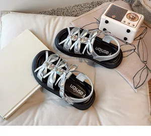 Detailed view of silver girl's sandals with rhinestone bows and thick black soles.
