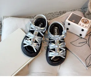 Detail of girls' silver sandals with elegant bows and shimmering gem accents.