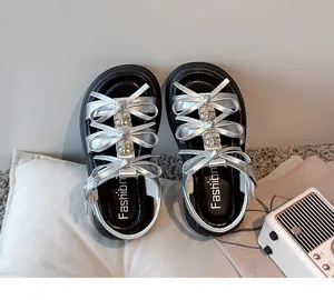Detailed view of silver girl's sandals with elegant bow accents and thick soft soles