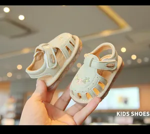 Nahaufnahme von beigen Kleinkindersandalen mit Blumenstickerei und hohlem Design-Stil