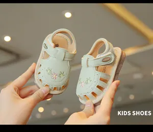 Nahaufnahme von minzgrünen, atmungsaktiven Hohlstoffsandalen mit Blumenstickerei für Babys