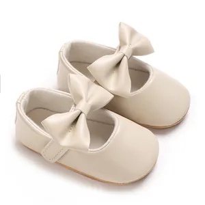 Detailansicht von cremefarbenen Baby-Mary-Janes mit großen Schleifen und weichen Sohlen.