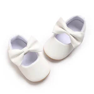 Nahaufnahme weißer Baby-Lauflernschuhe mit eleganter Schleife und weicher Gummisohle
