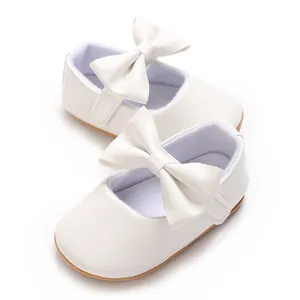 Detail von weißen Babyschuhen mit Schleife und weicher, rutschfester Gummisohle