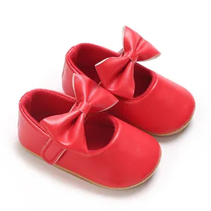 Nahaufnahme von roten Babyschuhen mit großer Schleifendekoration auf weißem Grund