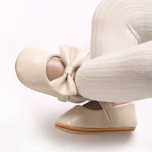 Nahaufnahme eleganter beiger Baby-Lauflernschuhe für Mädchen mit Schleife und Gummisohle