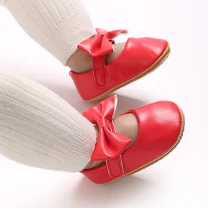 Nahaufnahme von stilvollen roten Babyschuhen mit Schleife und weicher rutschfester Gummisohle
