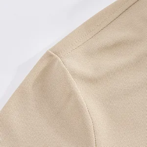 Detail view of the breathable beige mesh fabric and reinforced seams of a men's polo shirt