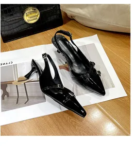 Dettaglio di scarpe décolleté a punta in vernice nera con cinturino e fibbie eleganti