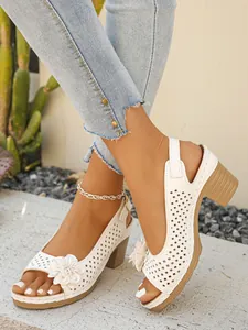 Detailed view of white chunky heel sandals with floral decoration and perforations
